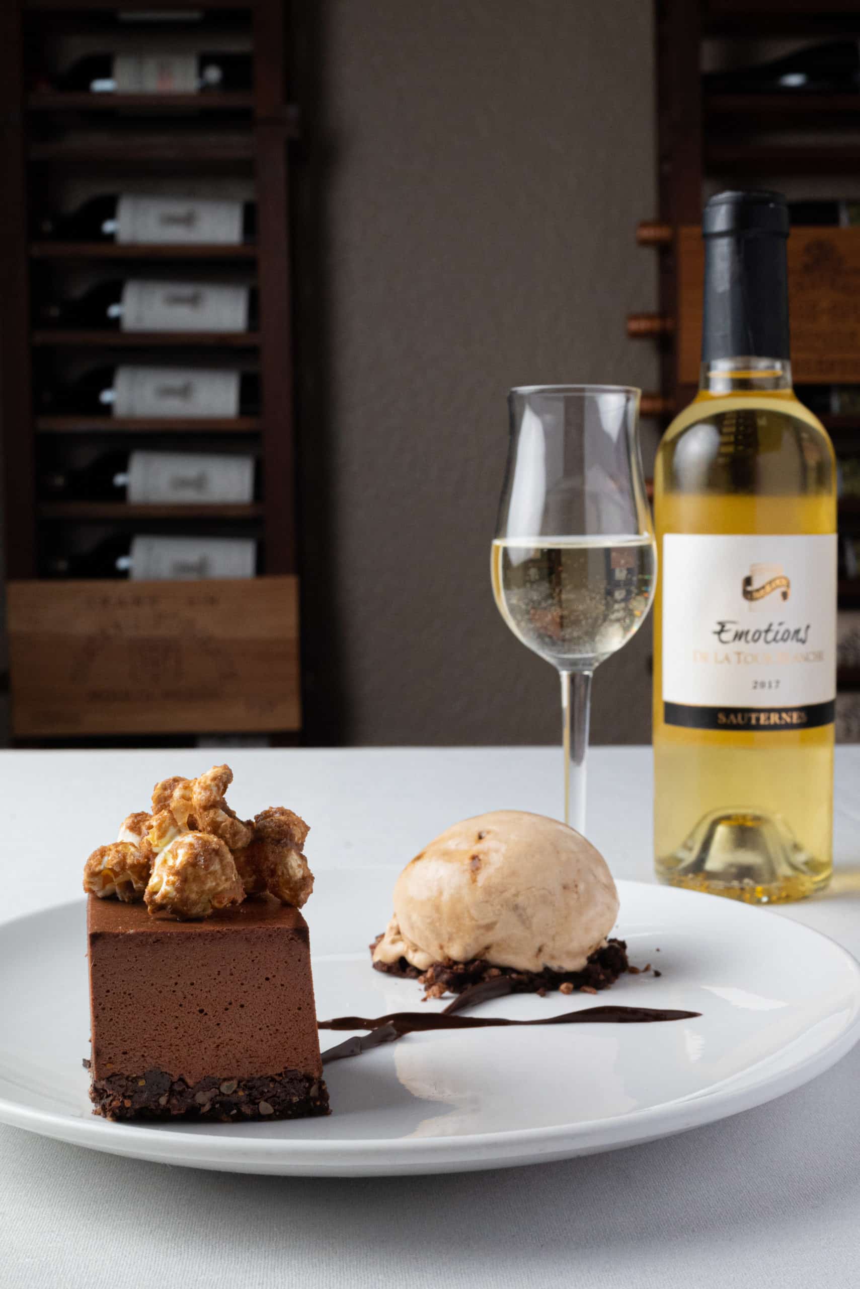 Vertical Image of Dessert plate with ice cream and chocolate cheese cake paired with white wine